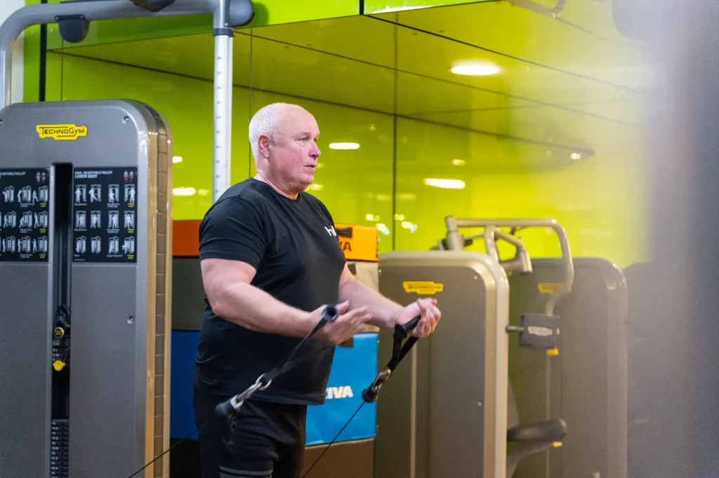 Older man using a Technogym cable resistance machine in the gym