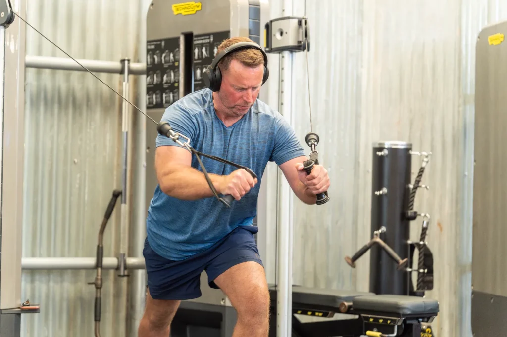 Man performing a cable crossover exercise on Technogym equipment at Blackshots leisure centre gym
