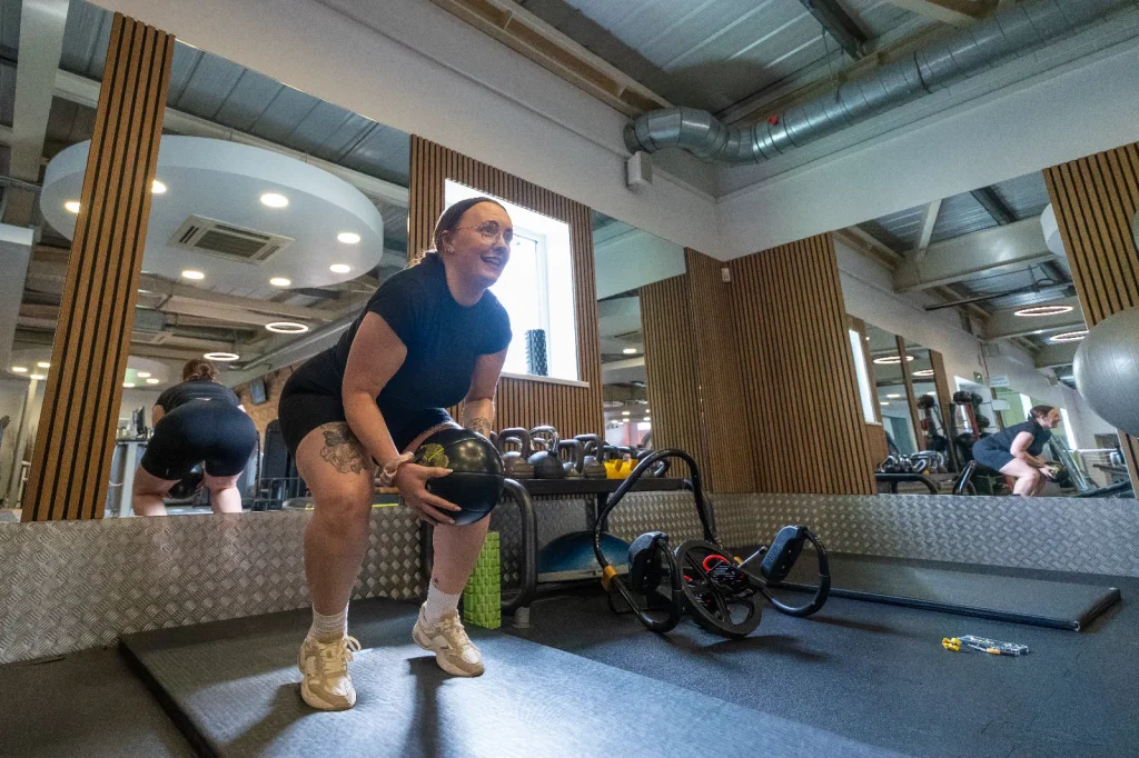 Woman exercising with a medicine ball in the functional training area of a leisure centre gym