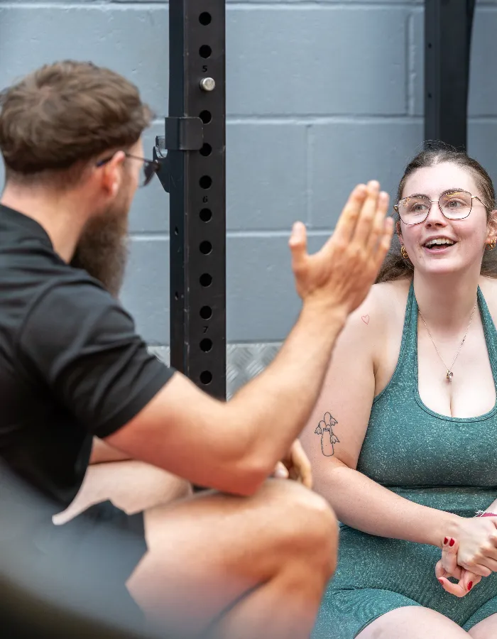 Personal trainer giving a high five to a female client during a workout session at the gym