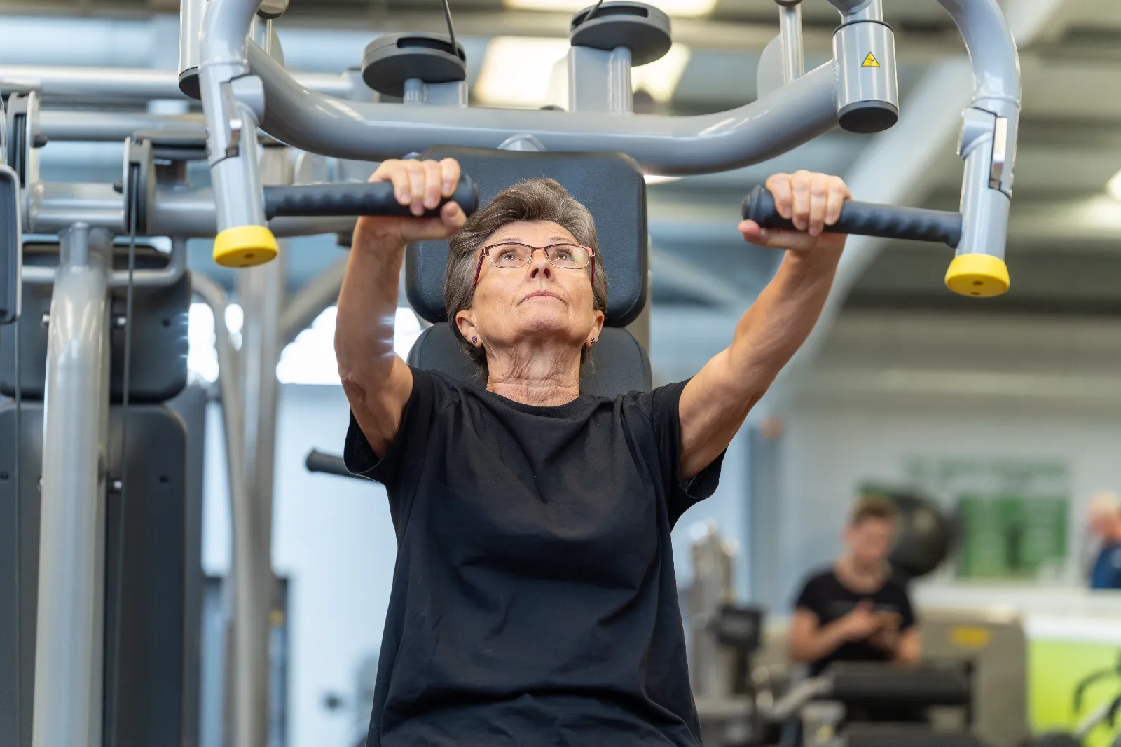 Older woman using the shoulder press machine at Blackshots leisure centre gym