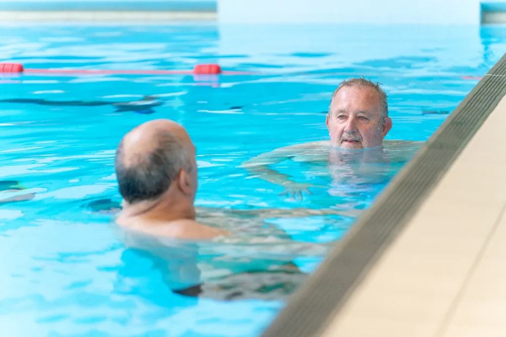 Two older men chatting in the swimming pool at an Impulse Leisure leisure centre