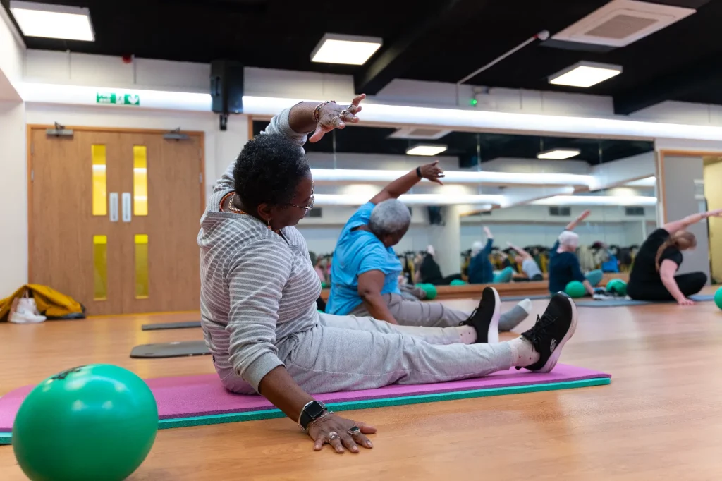 Members taking part in a wellbeing fitness class using exercise mats and small balls at a leisure centre