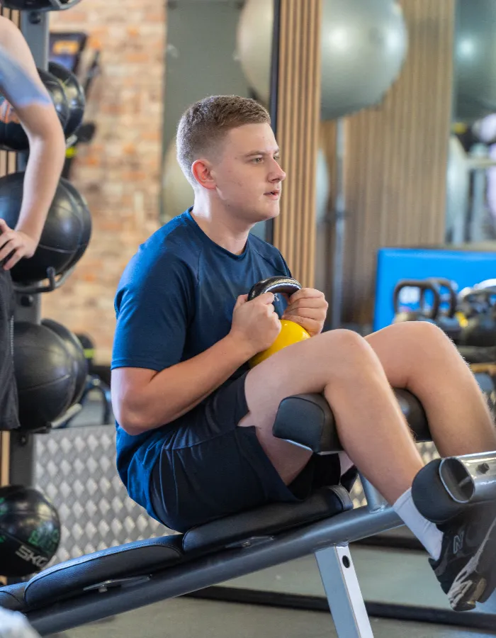 Young man exercising with a kettlebell in the free weights area at Corringham leisure centre gym