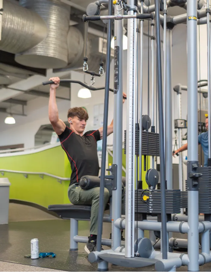 Young man using the lat pull-down machine at Blackshots leisure centre gym