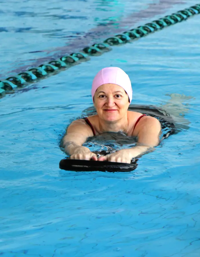 Adult woman using a kickboard during a crash course swimming lesson at an Impulse Leisure pool