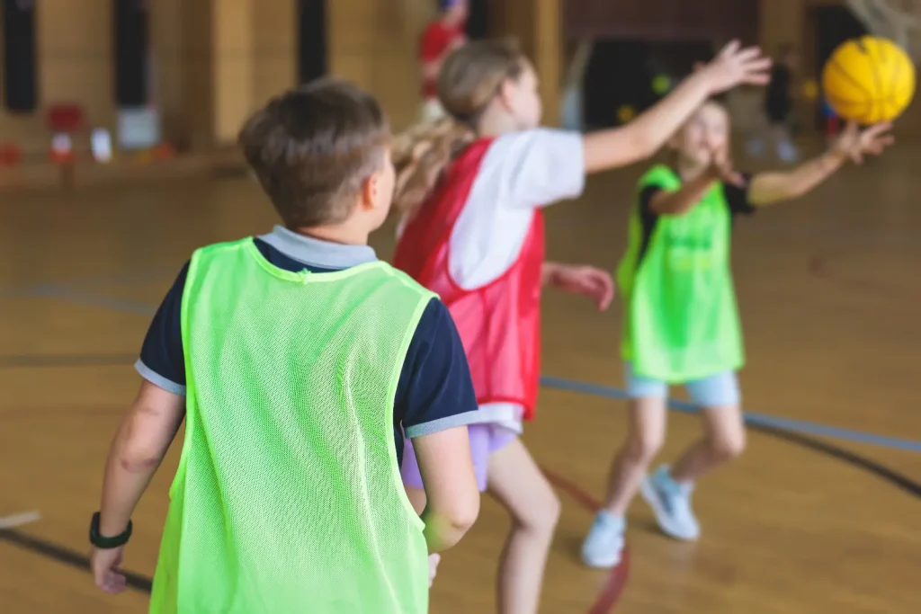 Children playing a team ball game during a junior fitness session at a leisure centre.
