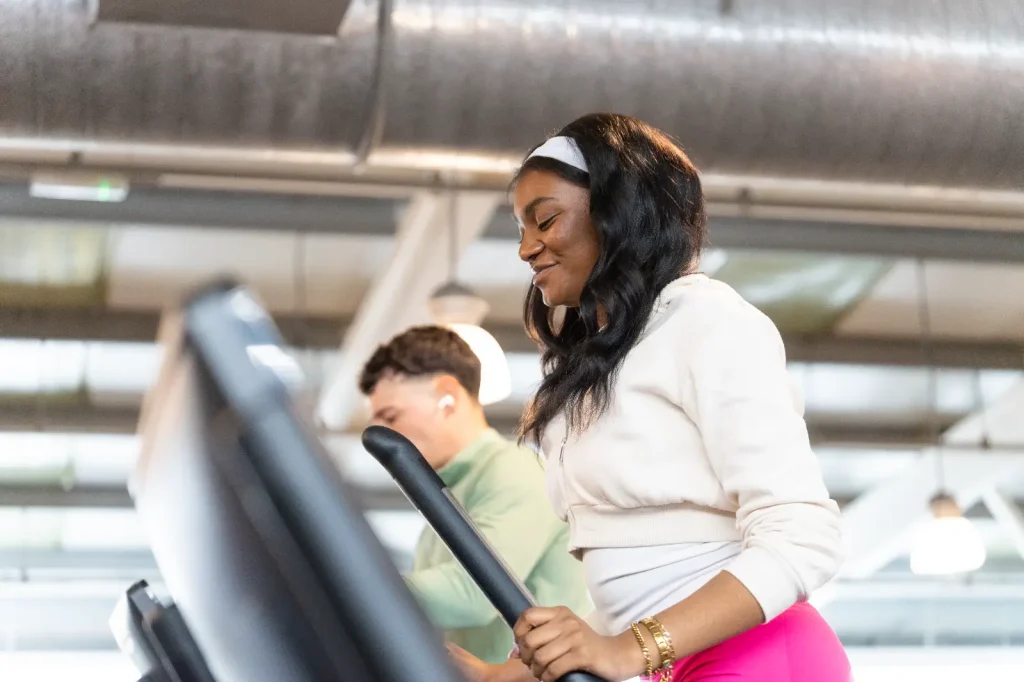Young woman using a Technogym cross trainer machine at Blackshots Impulse Leisure centre
