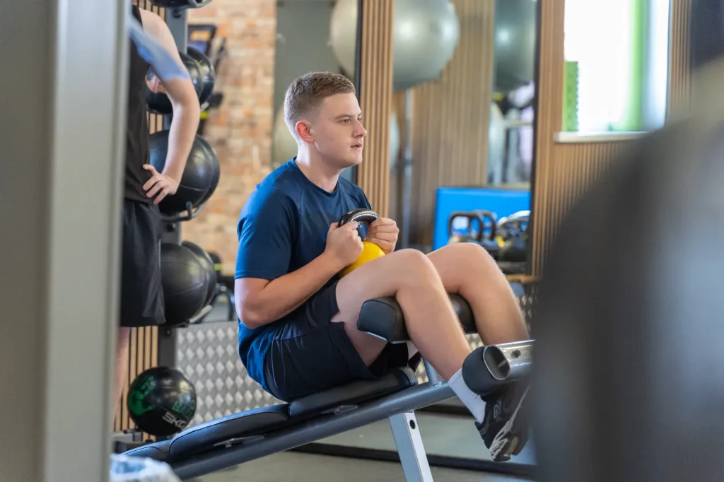 Young man performing a kettlebell exercise on a gym bench at Corringham Impulse Leisure centre