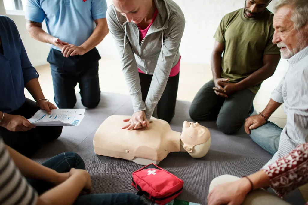 A lady, demonstrating emergency first aid, on a dummy to a group.