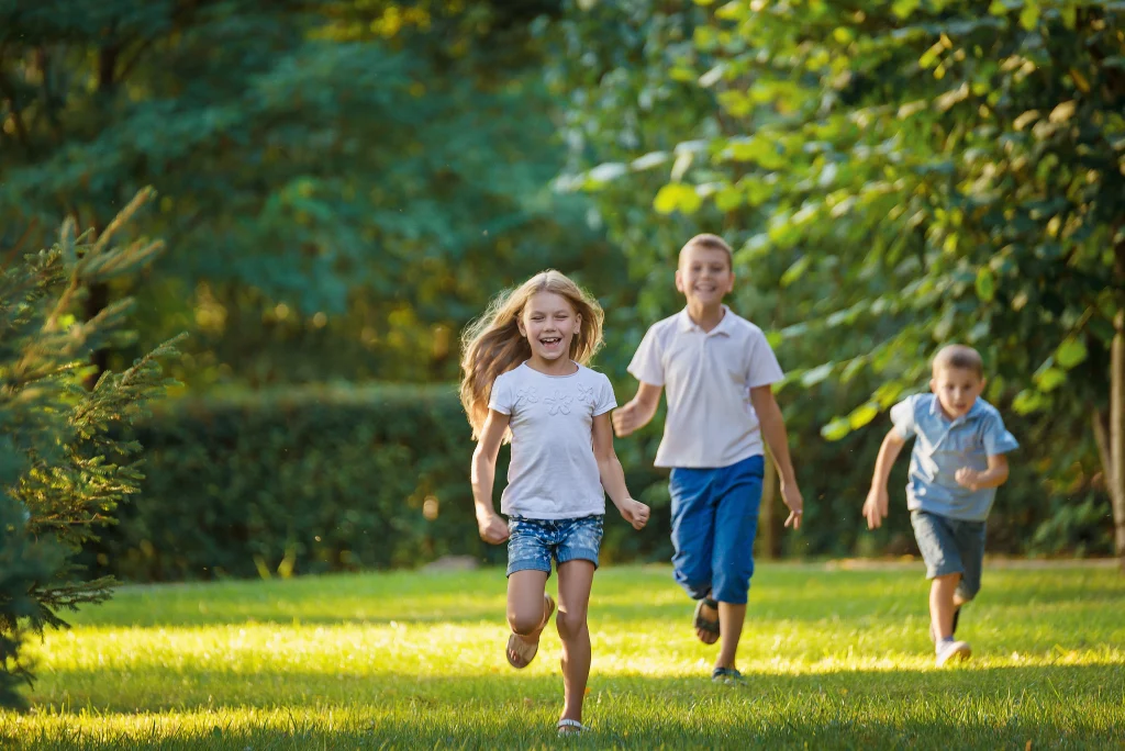 a group of children running across a field on a sunny day.