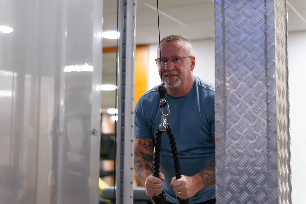 Man performing tricep pushdowns on a cable machine in the gym