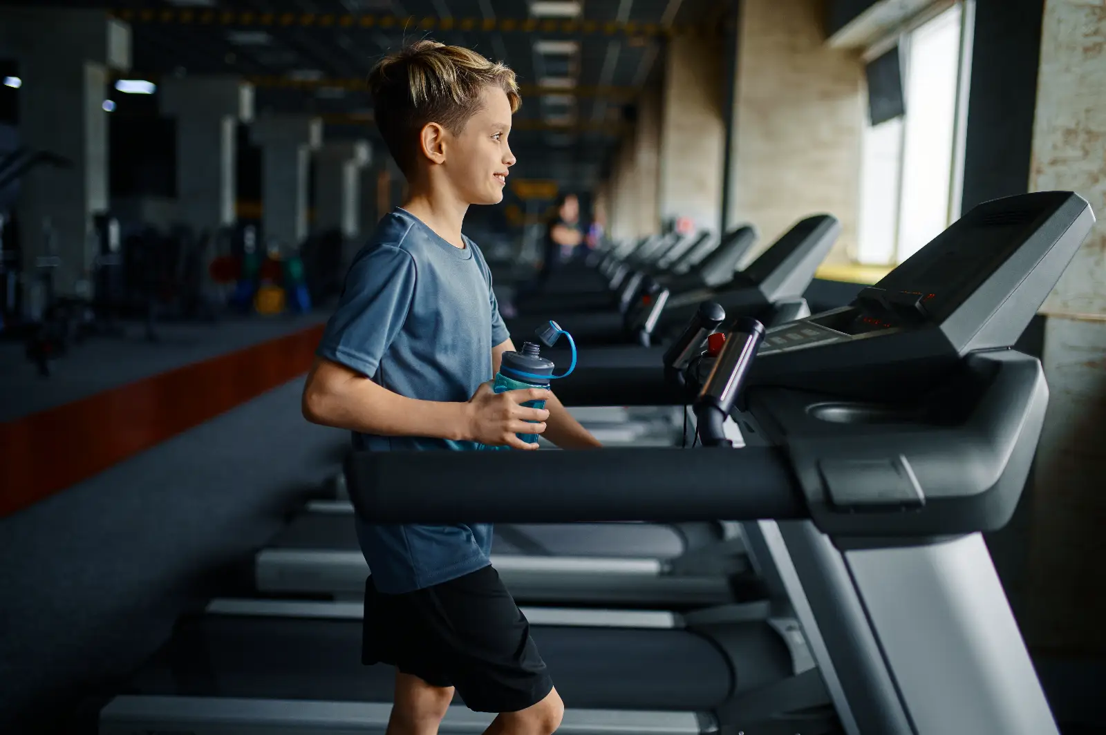 Young boy running on treadmill holding water bottle at Corringham leisure centre gym