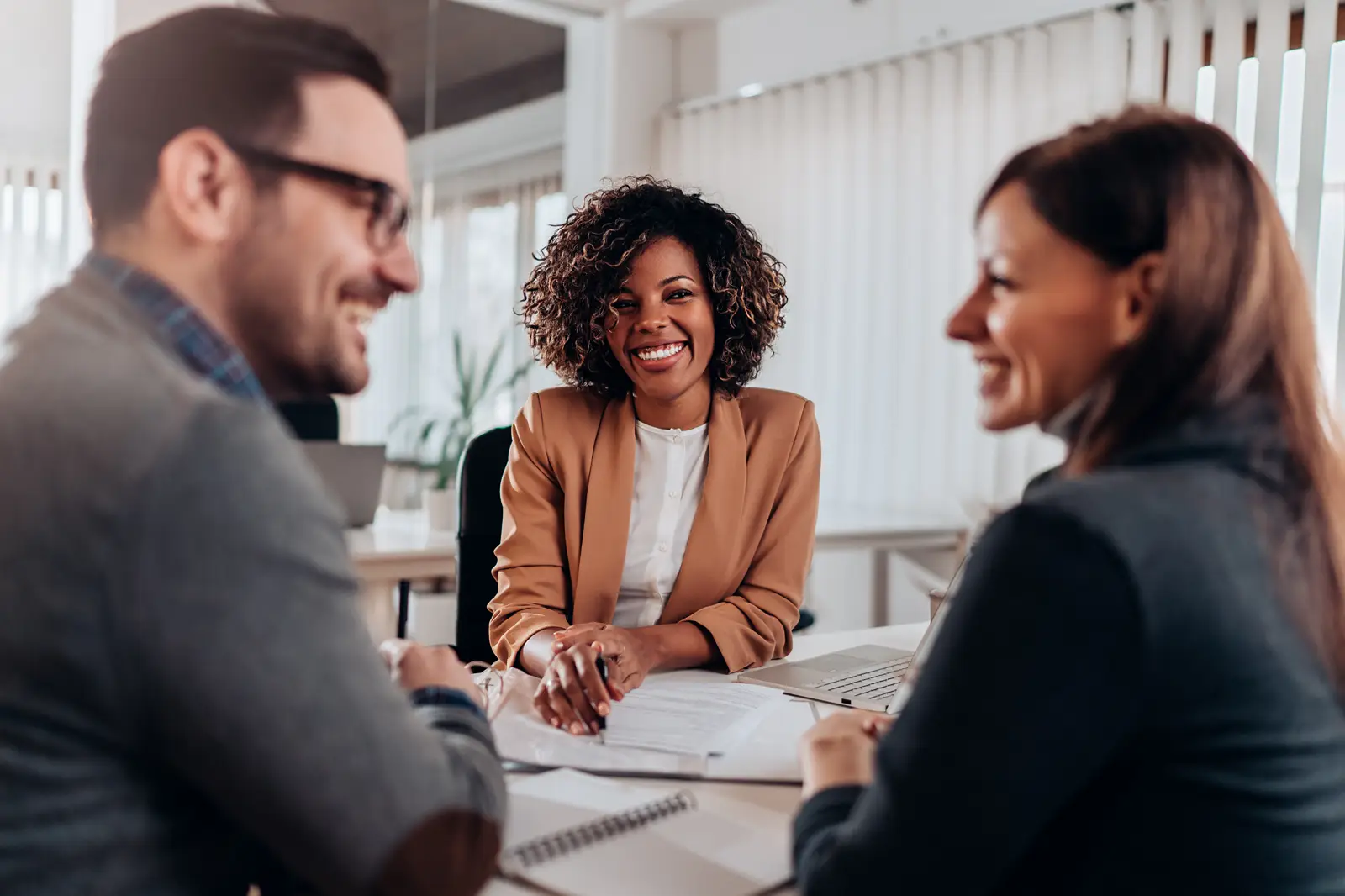 Couple consulting with a female financial manager at the bank about real estate loan