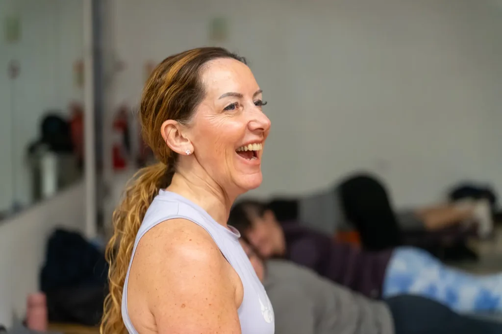 Lady, with her hair in a ponytail, smiling during a fitness class.