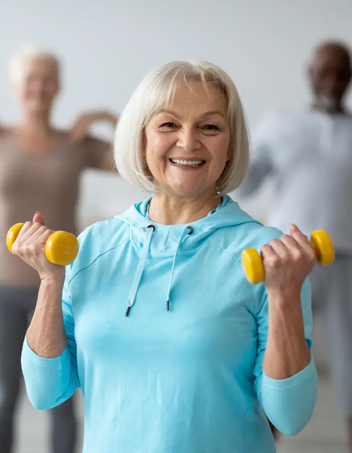mature lady holding free weights, during an exercise class.